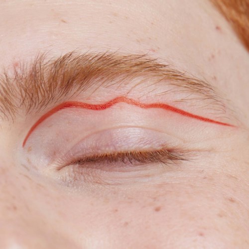Red line drawn on eyelid, above eyebrow, marking a shape.