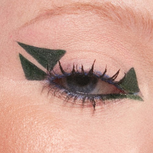 A person's eye with creative black and green geometric eye makeup design.