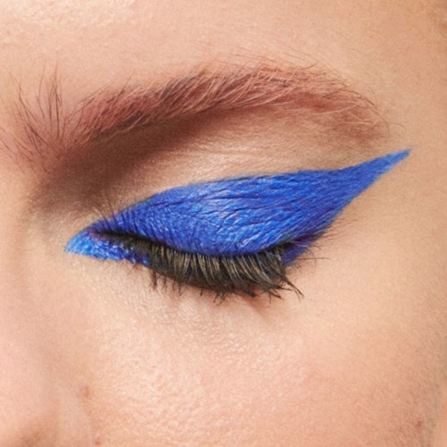 Close-up of eye with bold blue eyeshadow and long eyelashes.