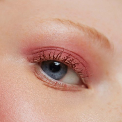 Närbild av en persons öga med makeup, visar blå färg och långa ögonfransar.