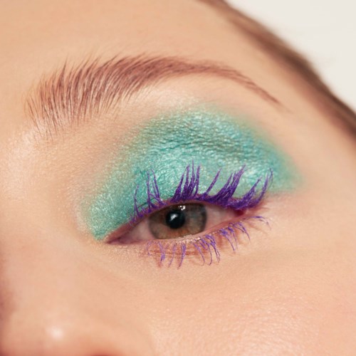 Close-up of eye with bright turquoise eyeshadow and purple mascara on lashes.