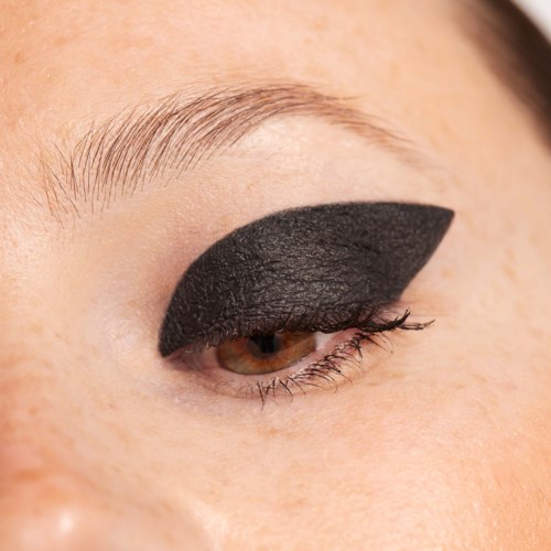 Close-up of a person's eye with bold, black eyeshadow covering the eyelid.