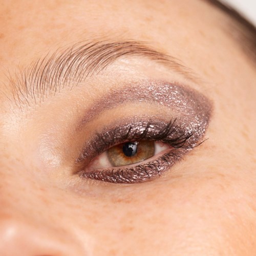 Närbild av ett makeup-öga med glitterögonskugga, eyeliner och långa ögonfransar.