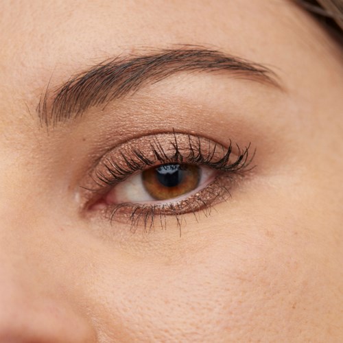 Close-up of a brown eye with long eyelashes, smooth skin, and well-shaped eyebrow.