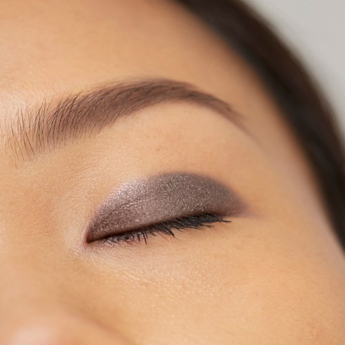 Eyes with closed eyelids showing makeup, with well-groomed eyebrow and smooth skin.