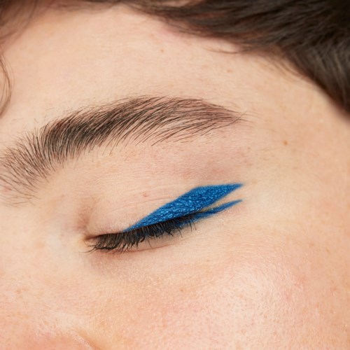 Close-up of a person's closed eye with bright blue eyeshadow and dark eyelashes.