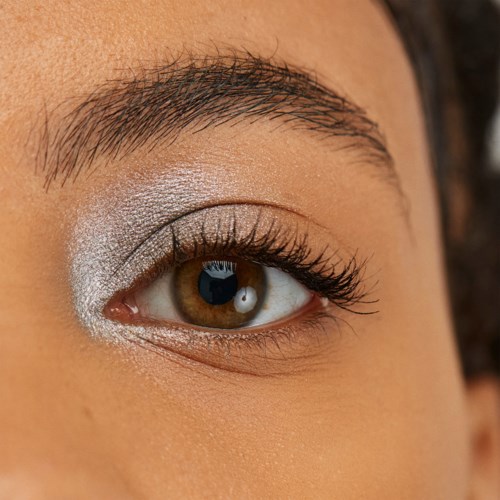 Close-up of a person's eye with eye makeup and neatly groomed eyebrow.