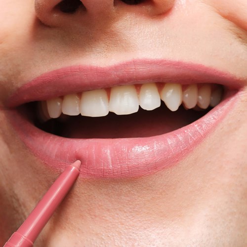 Close-up of a person's smiling mouth with pink lipstick and white teeth.