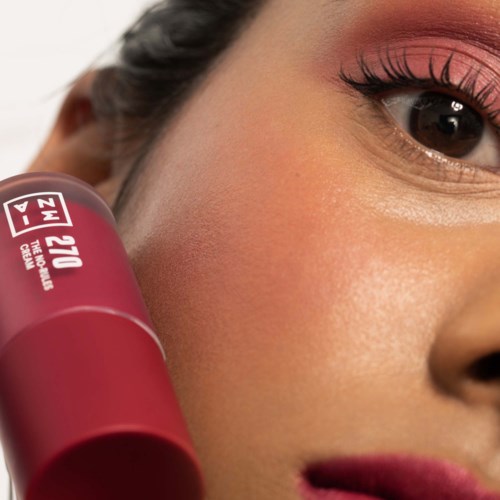 Close-up of a woman's face showing eye makeup and a lipstick tube.