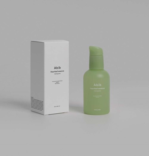 Een groene fles met 'Abib Heartleaf Essence' naast de witte doos.