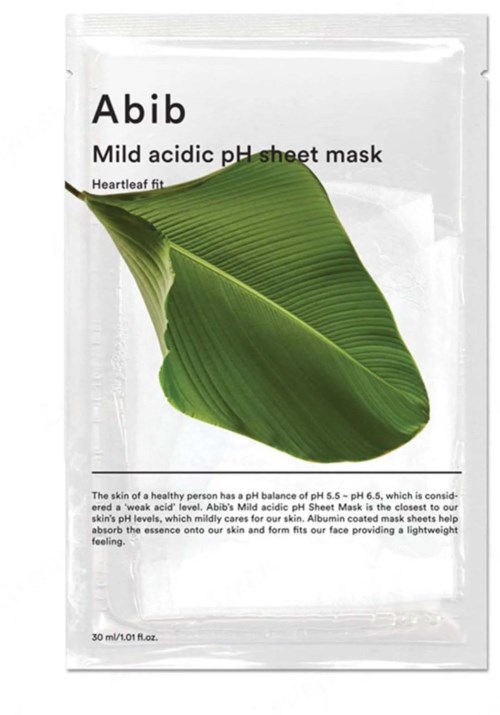 Een groen blad ligt op een witte verpakking met 'Abib' en 'mild acidic pH sheet mask' voor huidverzorging.