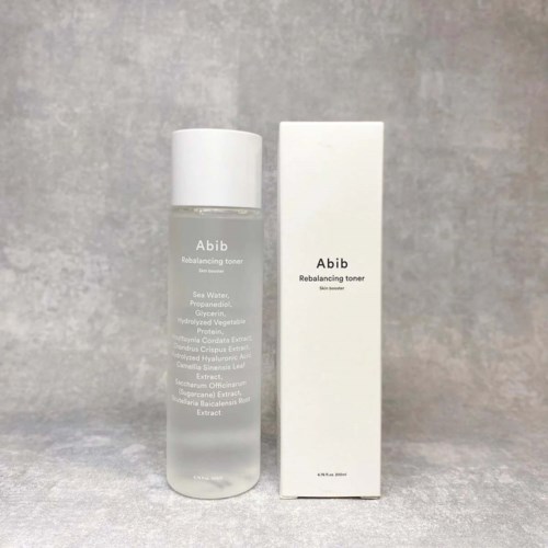Een doorzichtige fles Abib Rebalancing Toner naast een witte doos met zwarte tekst. De fles is gedeeltelijk doorzichtig, met vloeistof zichtbaar.
