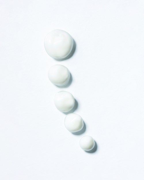 Vijf witte tabletten gerangschikt in een dalende lijn op een witte achtergrond.