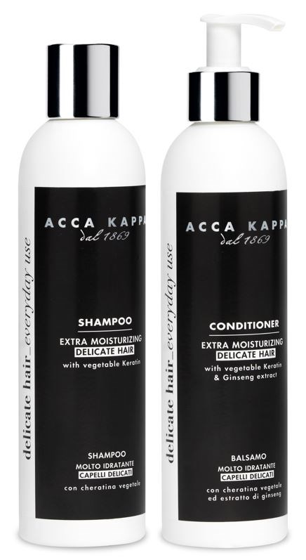 To hvite flasker, en sjampo og en balsam, med svarte etiketter og sølvkapsler, for hårpleie.