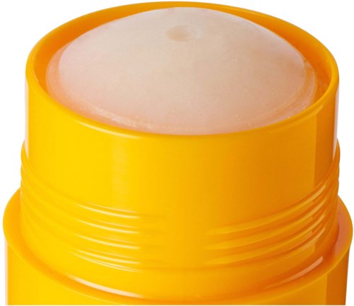 En gul beholder med et hvitt, fast balsam innvendig, muligens lipbalm eller kosmetikkprodukt.