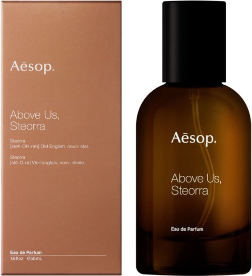 Ein Parfüflasche und eine Schachtel mit der Beschriftung Aesop Above Us, Steorra, mit einfachem Text, braunen und schwarzen Farben.