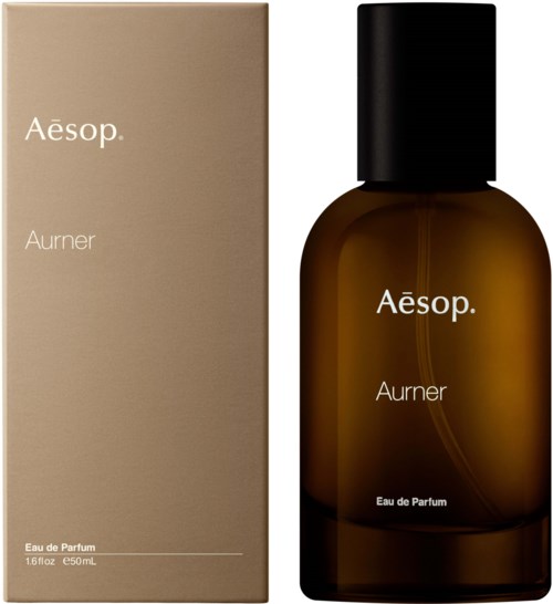 Eine braune Parfüflasche mit schwarzem Deckel und eine beigefarbene Schachtel, beide mit der Aufschrift 'Aesop Aurier Eau de Parfum'.