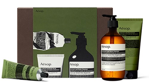 Eine Sammlung von Aesop-Hautpflegeprodukten, einschließlich Tuben, Flaschen und einer Box in Grün, Schwarz und Bernsteinfarben.