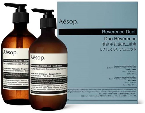 Two brown bottles and a light blue box, all labeled Aesop, with names of aromatic hand and face care products.