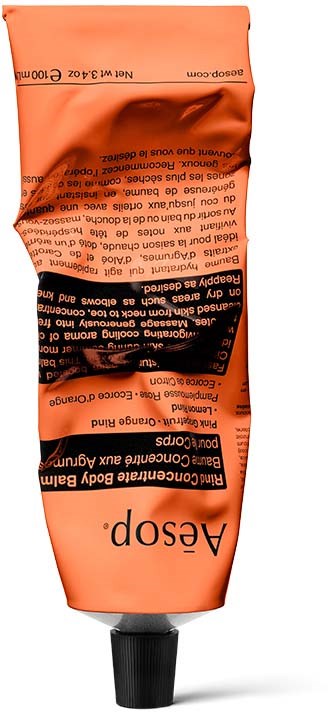 Eine Tube mit schwarzer Kappe, orange- und schwarz beschriftet, mit Text und zerknittertem Aussehen.