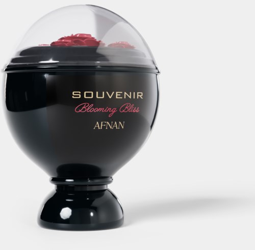 Een zwarte, ronde container met doorzichtige deksel, versierd met roze bloemen en gouden tekst die zegt "Souvenir Blooming Bliss AFNAN."