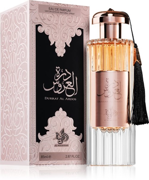 En rosa parfyllrör med en svart tofs bredvid sitt utsmyckade rosa och svart box med arabiska tecken.