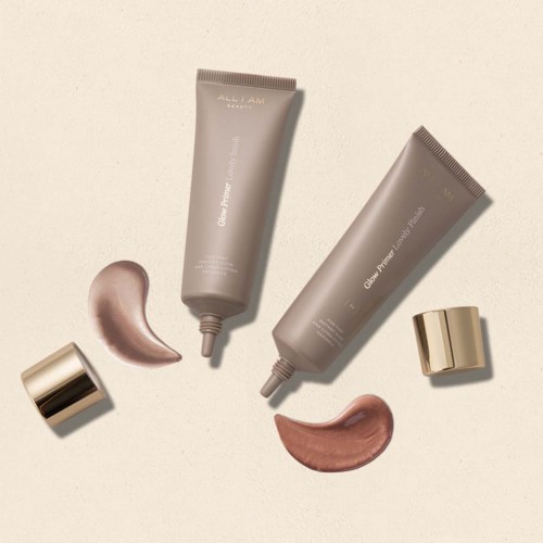 Two gray tubes with gold caps and two streaks of cream or lotion on a light background.