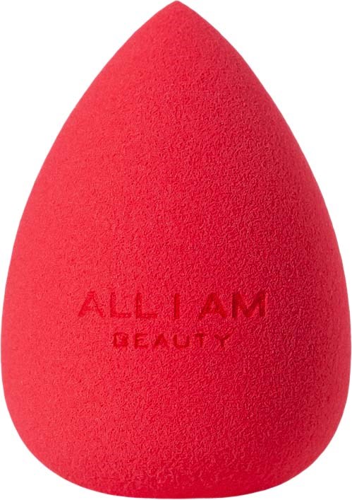 A red makeup sponge with the words "ALL I AM BEAUTY" on it, shaped like a teardrop.