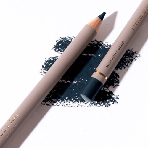 A beige pencil with a black tip lies on blue and black ink smudges, accompanied by a white and blue pen.