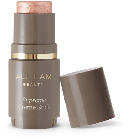 A gray tube of makeup stick with a gold ring and a beige cap, labeled 'ALL I AM BEAUTY Supreme Creme Stick.'