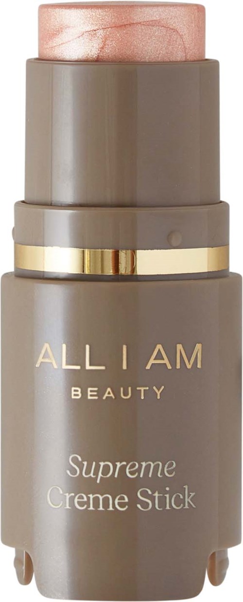 A grey and pink makeup stick labeled "ALL I AM BEAUTY Supreme Creme Stick" with gold accents.
