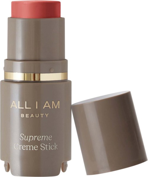 A gray bottle with a pink cap, labeled "ALL I AM BEAUIY Supreme Creme Stick". The cap is removed and placed beside.