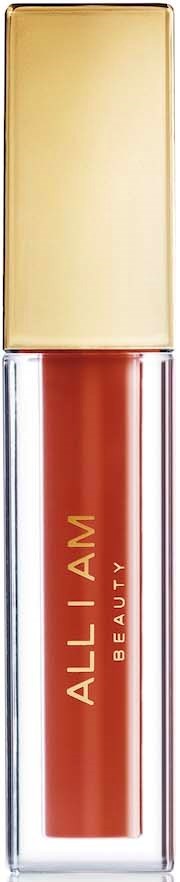 A lipstick with a gold cap and a transparent body showing red-orange color, branded 'ALL I AM BEAUTY.'