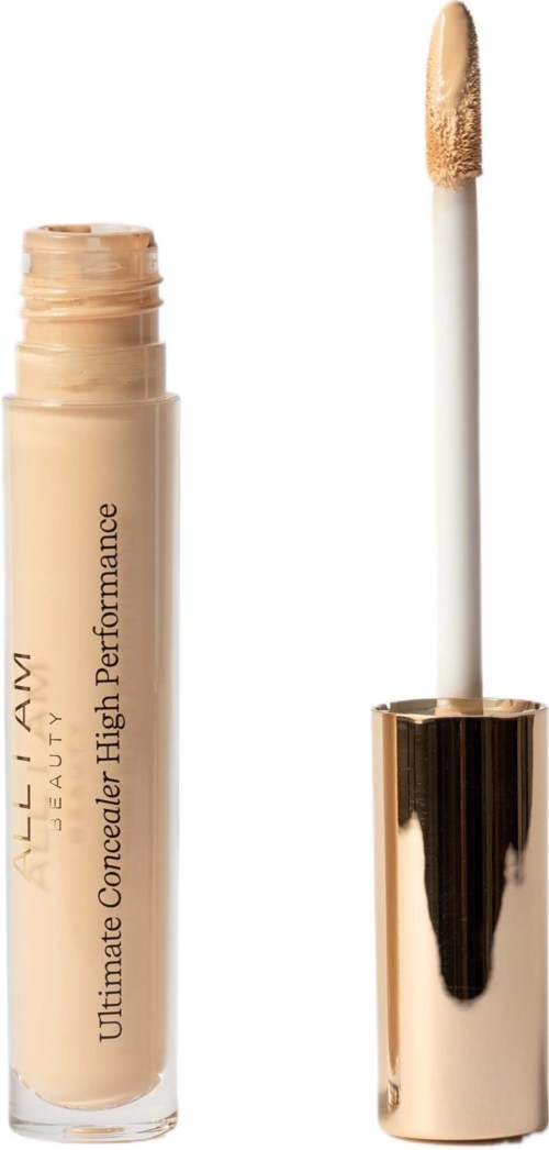 Een beige concealerbuis met een wit en goud applicatorspons ernaast.