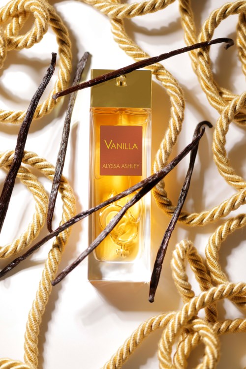 Eine Vanilleparfümflasche, umgeben von Vanilleschoten und goldenen Seilringen.