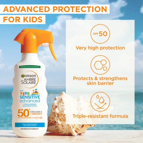Een zonnebrand sprayfles voor kinderen met SPF 50, zee en hemel op de achtergrond, en een grote rots.