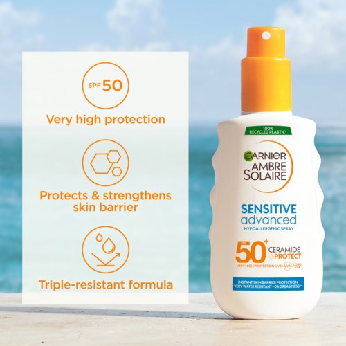 A sunscreen spray bottle on beach with SPF 50, high protection, and skin barrier benefits, in sunny weather.