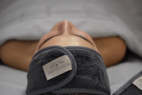 Eine Person liegt im Bett mit einer schwarzen Augenmaske, die die Augen bedeckt, und ruht ruhig.