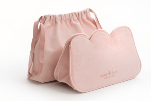 Ett mjukt rosa handbag med matchande väska, båda tillverkade av tyg, placerade mot en vit bakgrund.