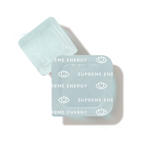 Ein weißer quaderförmiger Gegenstand mit kleinen blauen Ohren und zwei Blisterpackungen mit Tabletten, bezeichnet "Supreme Energy."