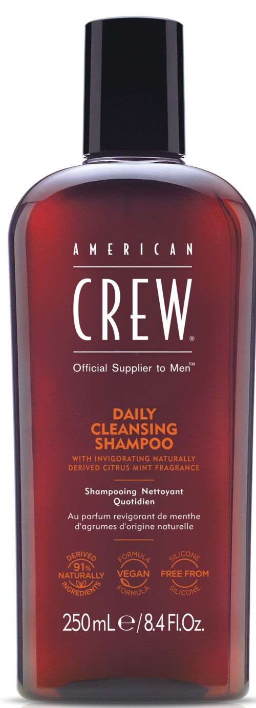 A bottle of American Crew Daily Cleansing Shampoo with black cap and reddish label.