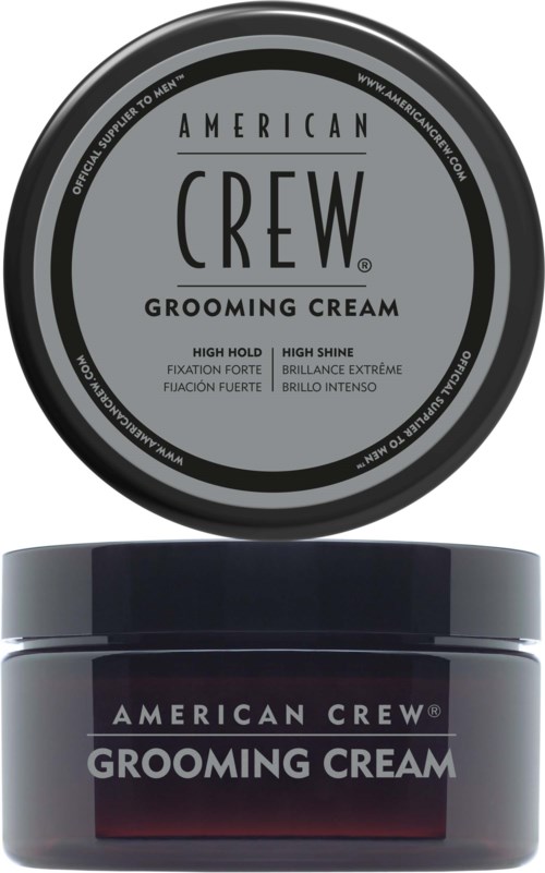 En rund beholder og lokk for American Crew Grooming Cream med tekst som beskriver fordeler som sterk hold og glans.