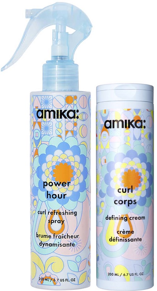 Two bottles of Amika hair products with colorful designs, one spray and one cream for styling.