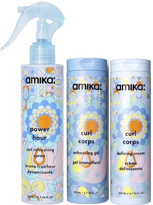 Three hair care products with colorful, floral-patterned labels, including a spray, gel, and cream for curls.