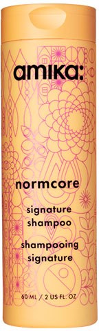 Amika: Normcore signaturschampo flaska med gula och rosa blommiga mönster. Text innehåller produktnamn och detaljer.