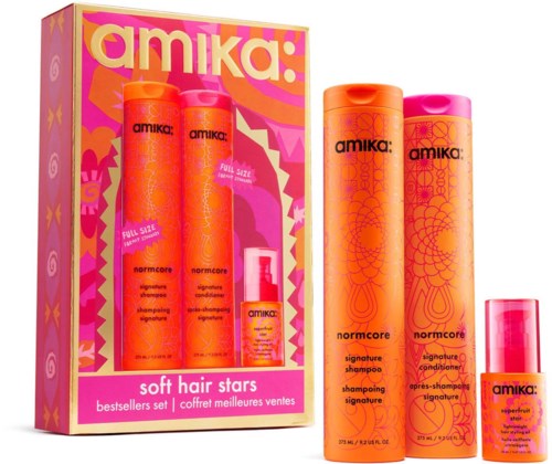 Set med Amika normcore signature sjampo, balsam og en liten hårpleieprodukt i rosa og oransje flasker, med fargerik emballasje.