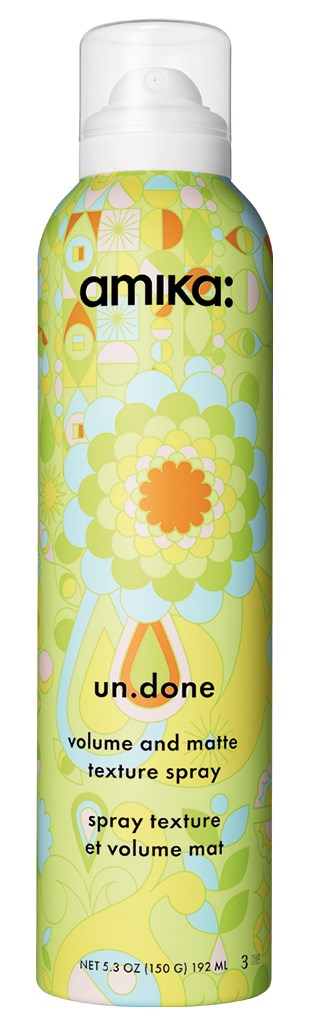 Eine Sprühdose mit buntem, blumenartigem Design. Beschriftet mit "amika: un.done" für Volumen und matte Textur.