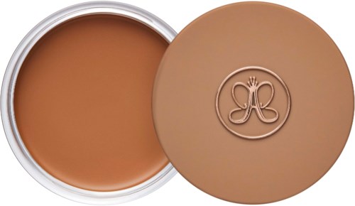 Ein runder Behälter mit brauner Creme und einem Deckel mit eingedrücktem Logo.
