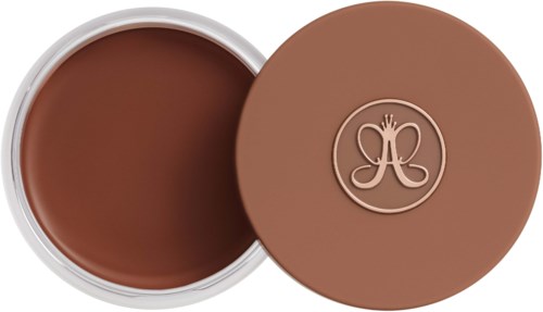 A round, brown container with a lid featuring a logo, filled with a creamy, brown substance.
