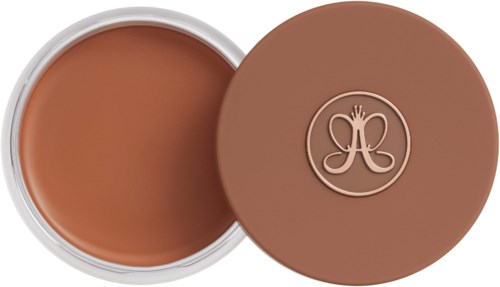 Round container with brown makeup, lid with embossed logo, open showing the product inside.